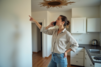 Femme inquiète pointant un plafond humide dans un appartement